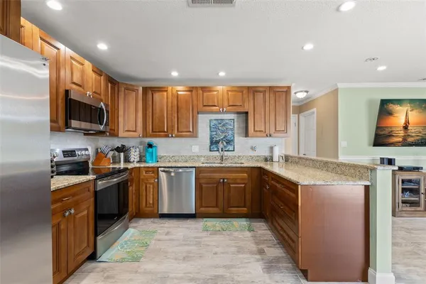a kitchen with stainless steel appliances granite countertop wooden cabinets a sink a stove a microwave and a refrigerator