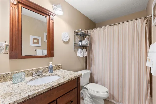 a bathroom with a granite countertop sink toilet and mirror