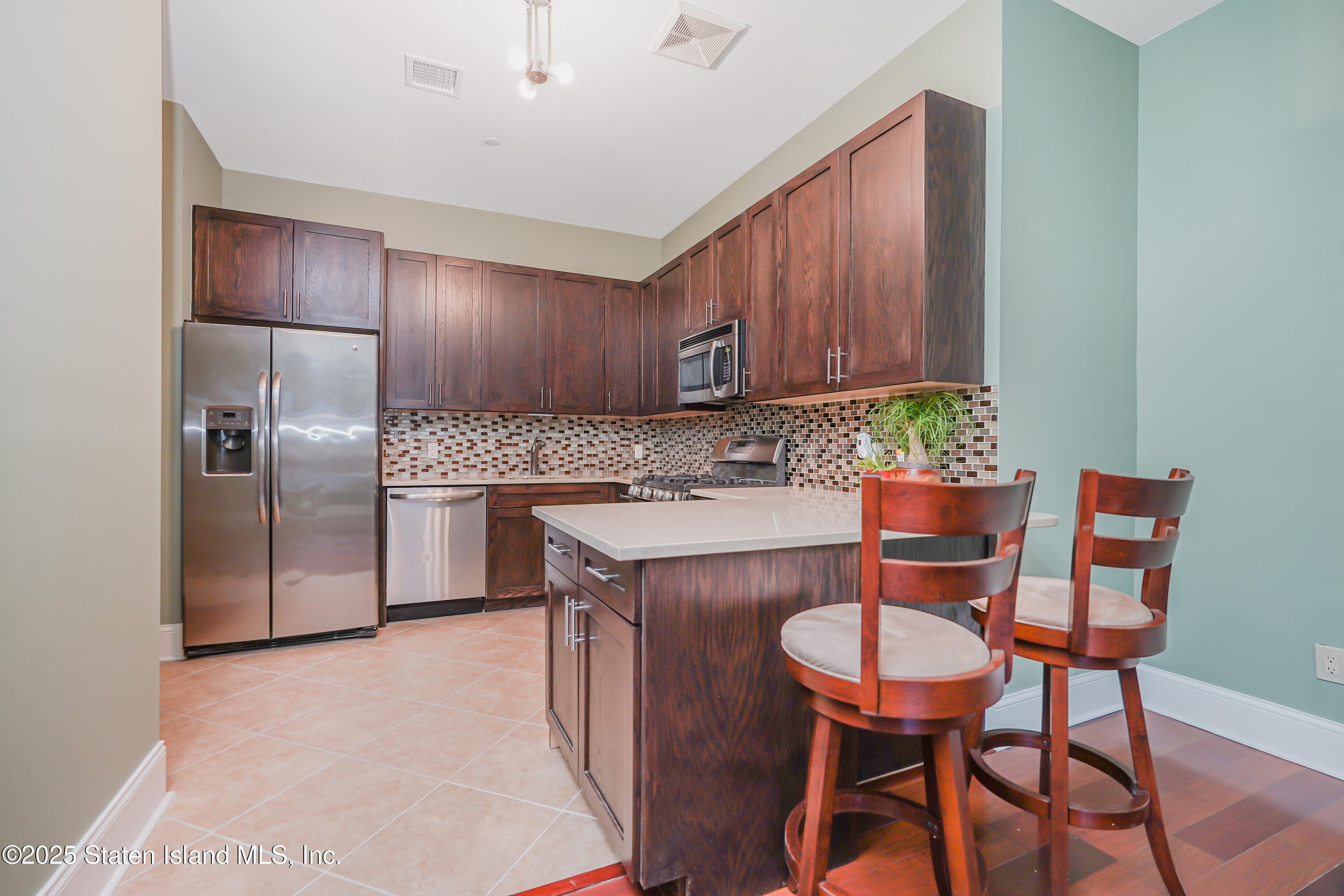 90 Bay Street Landing, Unit 1E Staten Island, NY 10301 - Photo 11 of 43 a kitchen with stainless steel appliances kitchen island a table chairs in it and wooden floors