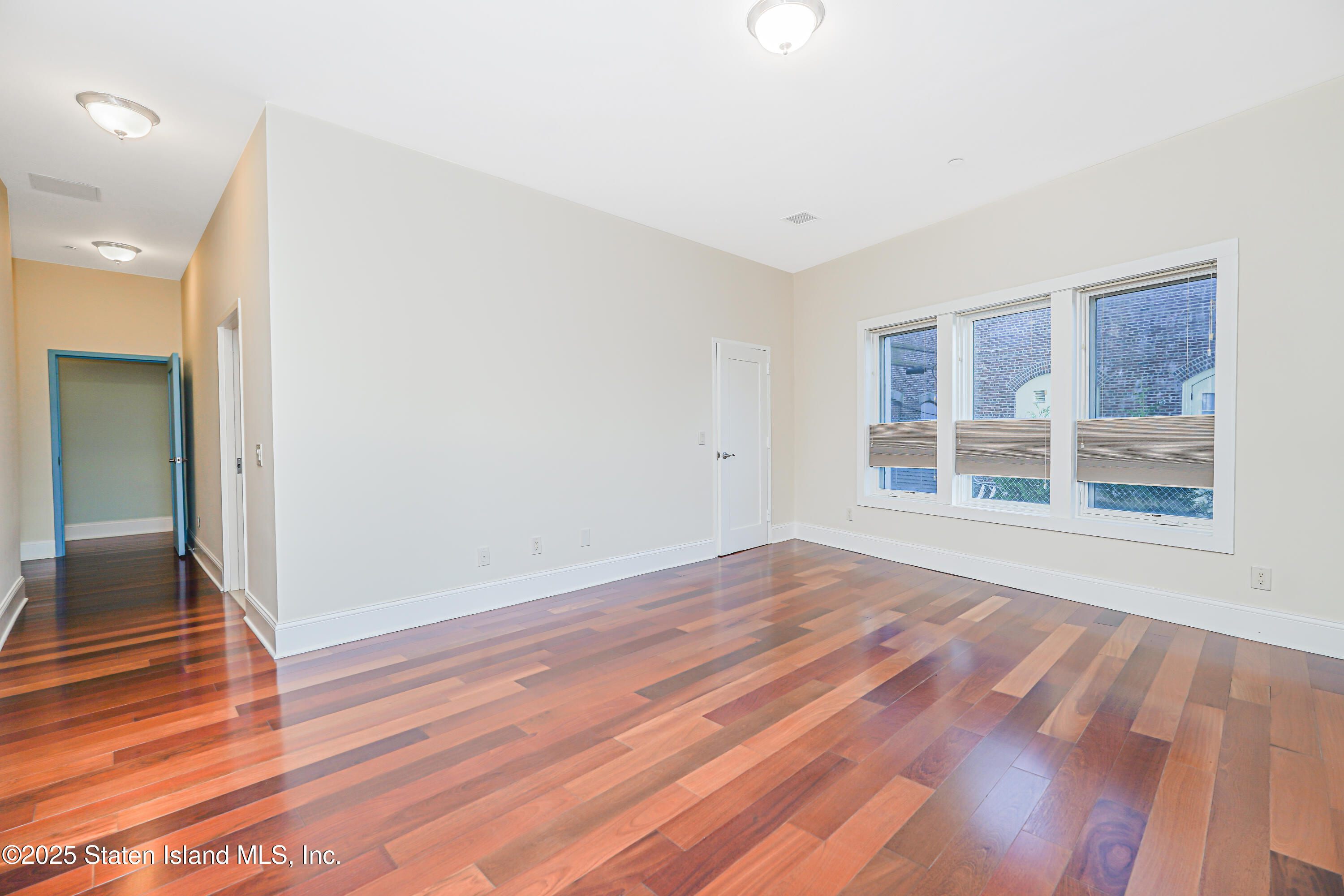 90 Bay Street Landing, Unit 1E Staten Island, NY 10301 - Photo 18 of 43 an empty room with wooden floor and windows