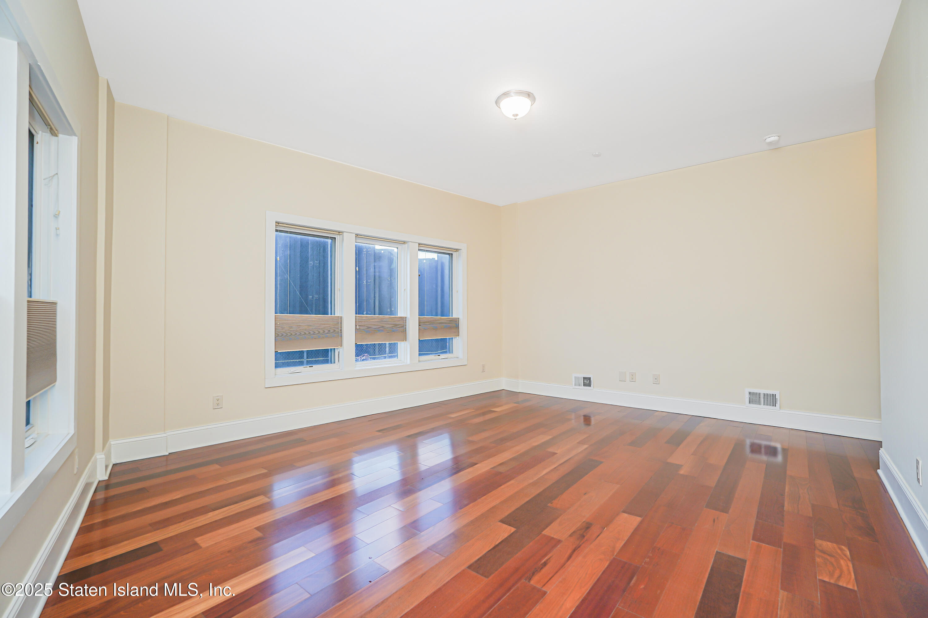 90 Bay Street Landing, Unit 1E Staten Island, NY 10301 - Photo 21 of 43 an empty room with wooden floor and windows