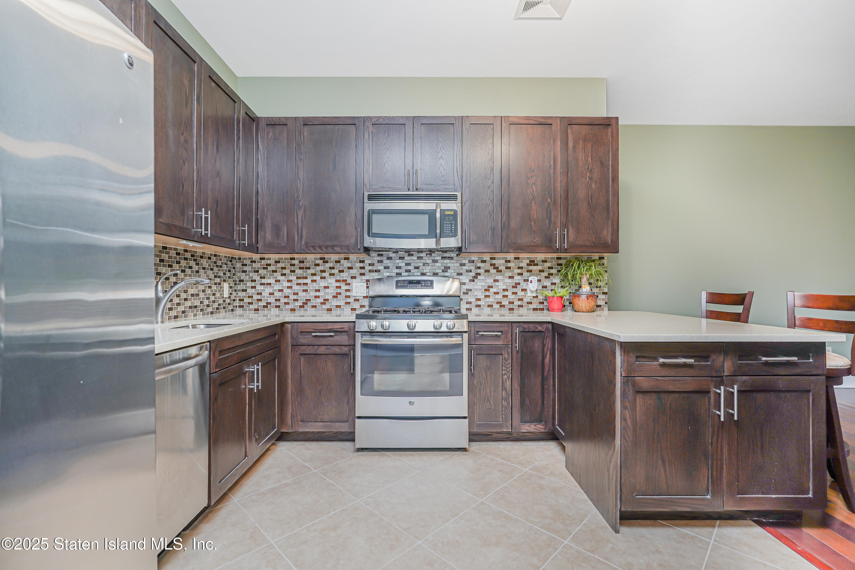 90 Bay Street Landing, Unit 1E Staten Island, NY 10301 - Photo 7 of 43 a kitchen with stainless steel appliances granite countertop wooden cabinets stove top oven and sink