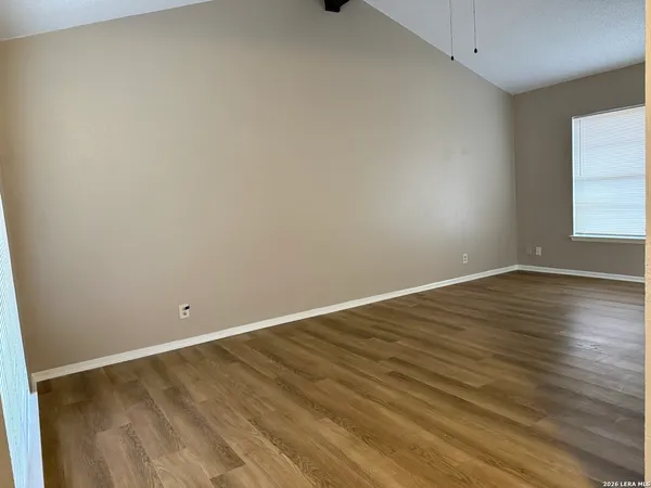 a view of an empty room with wooden floor and a window