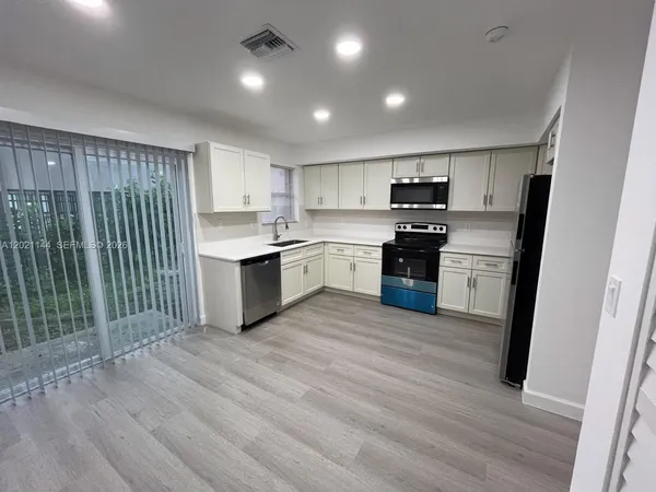 a kitchen with stainless steel appliances granite countertop a refrigerator and a stove top oven