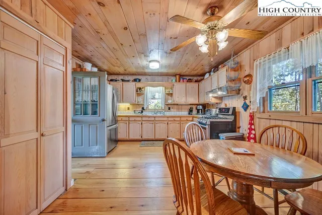 a kitchen with stainless steel appliances granite countertop a sink a stove a refrigerator with a dining table and chairs