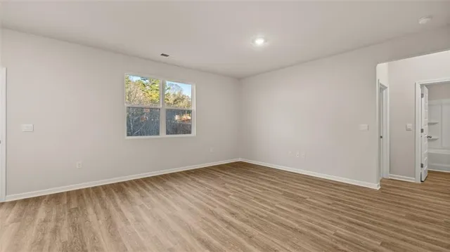 a view of an empty room with wooden floor and a window