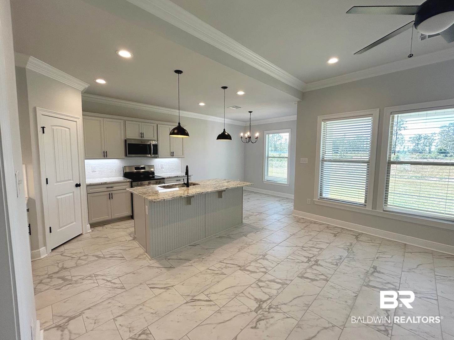 880 Sumter Loop Foley, AL 36535 - Photo 2 of 14 Kitchen featuring an island with sink, stainless steel appliances, crown molding, light stone countertops, and pendant lighting