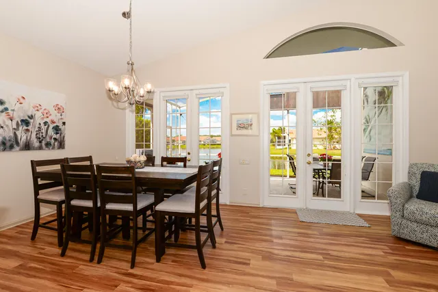 a kitchen with stainless steel appliances kitchen island granite countertop a refrigerator a stove a sink a dining table and chairs with wooden floor