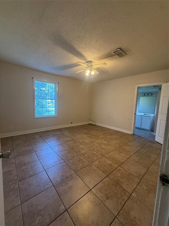 217 3rd St Pinehill Springhill, LA 71075 - Photo 11 of 23 Spacious interior room featuring neutral tile flooring, a ceiling fan with integrated lighting, and a white trim window