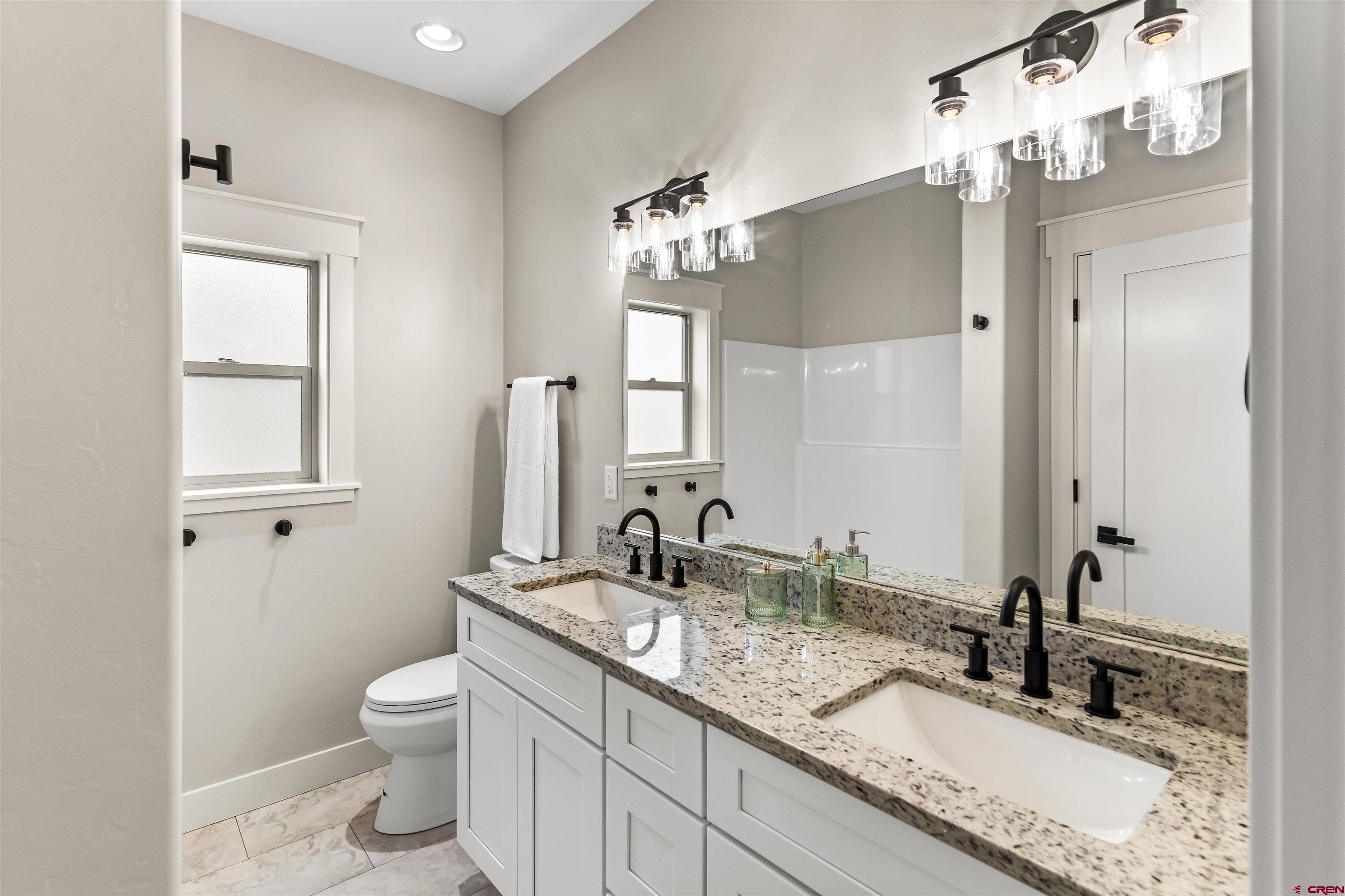 1533 Criterion Street Delta, CO 81416 - Photo 22 of 30 a bathroom with a granite countertop sink a toilet and a mirror