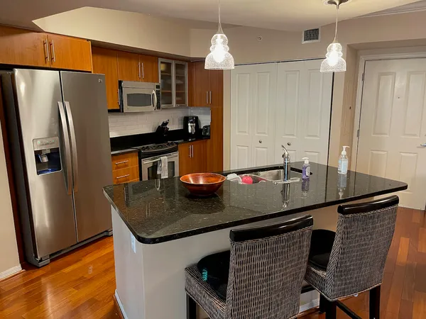a kitchen with granite countertop a sink cabinets and stainless steel appliances