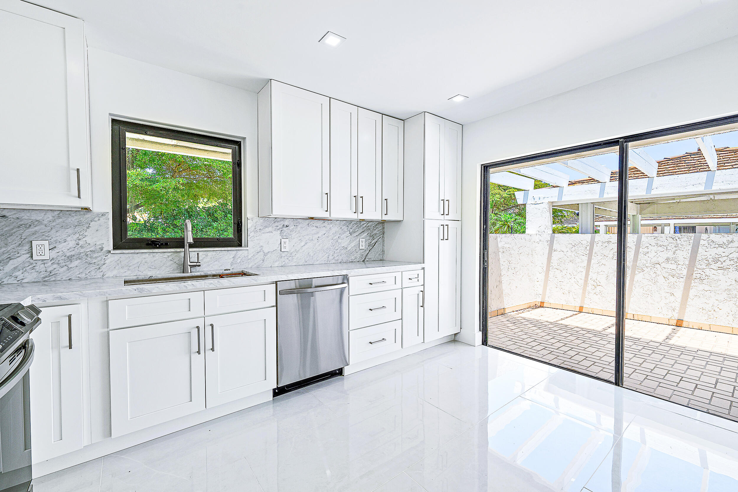 Undisclosed Address Jupiter, FL 33477 - Photo 13 of 30 a kitchen with white cabinets and a large window