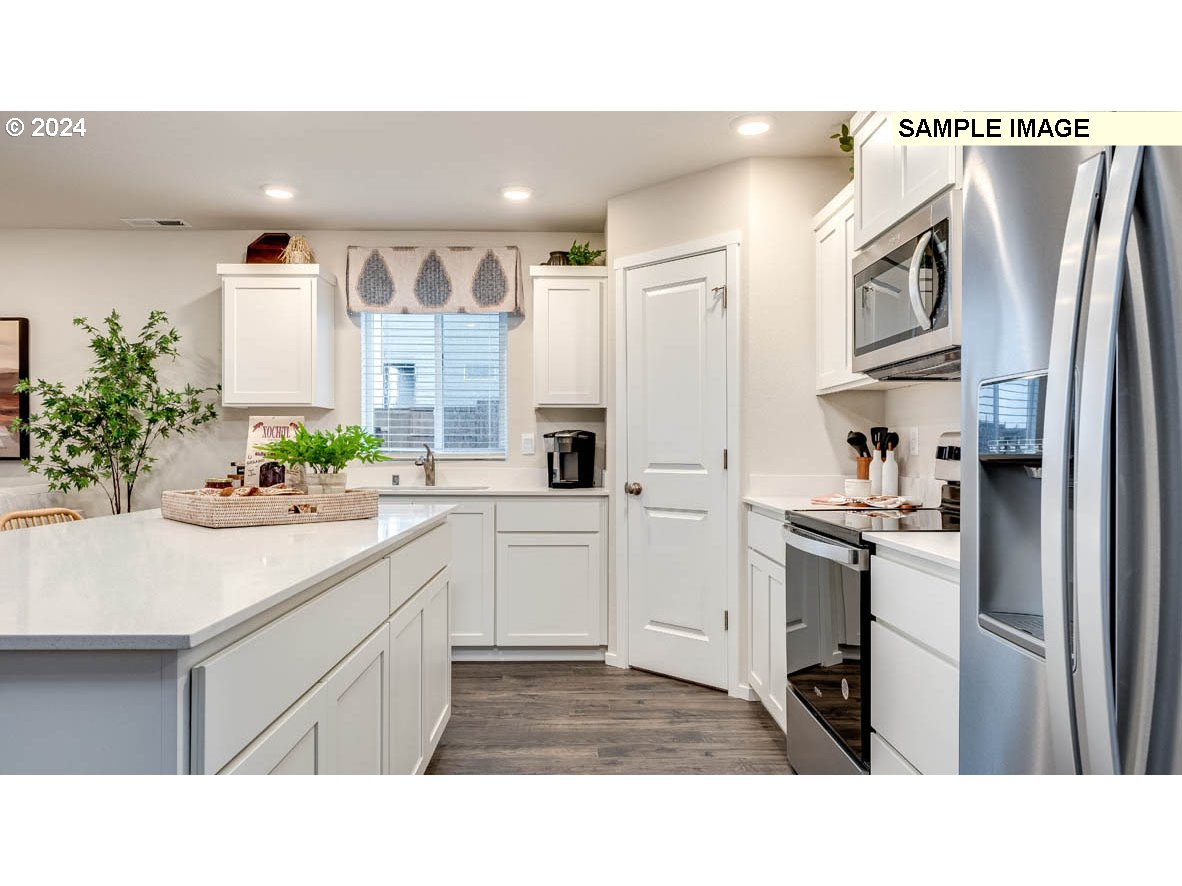 812 Northwest 175th Street Ridgefield, WA 98642 - Photo 9 of 25 a kitchen with stainless steel appliances a sink cabinets and a refrigerator