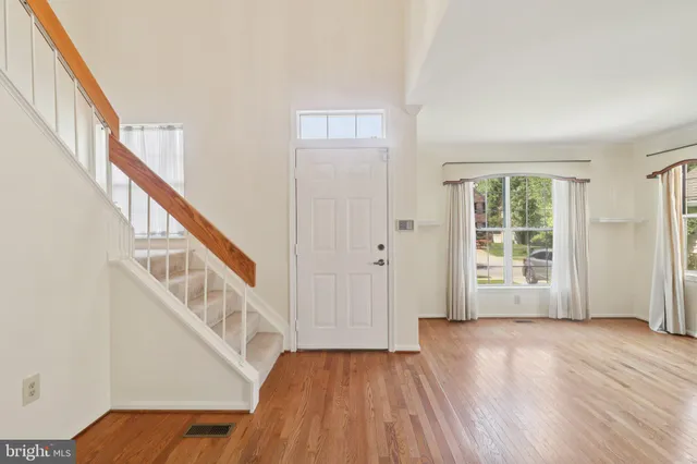 a view of an empty room with wooden floor and stairs