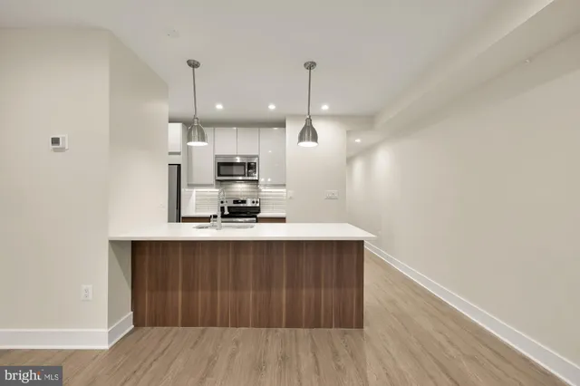 a kitchen with kitchen island stainless steel appliances a sink cabinets and wooden floor