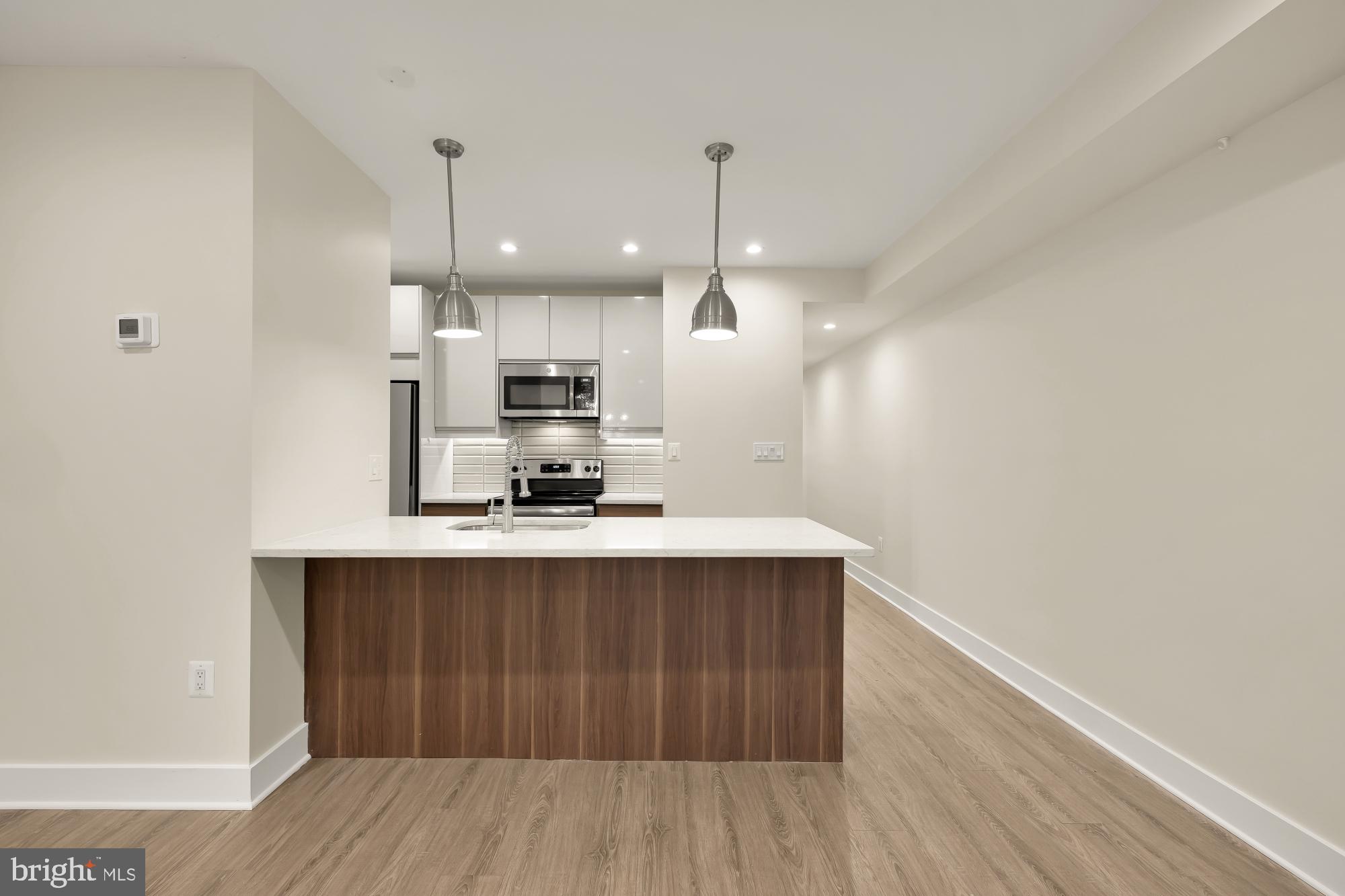 58 T Street Northwest, Unit 1 Washington, DC 20001 - Photo 6 of 27 a kitchen with kitchen island stainless steel appliances a sink cabinets and wooden floor