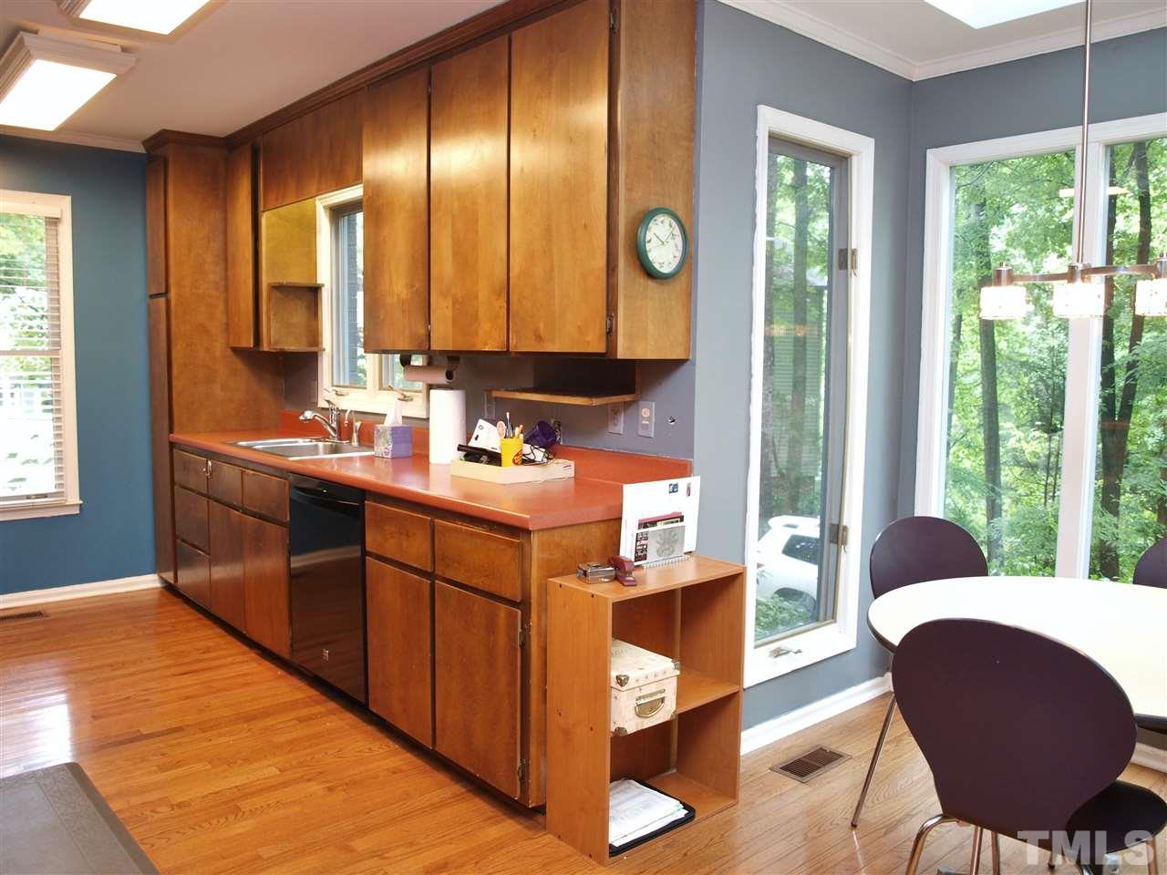 2955 Rue Sans Famille Raleigh, NC 27607 - Photo 5 of 21 a kitchen with kitchen island granite countertop a sink cabinets and a large window