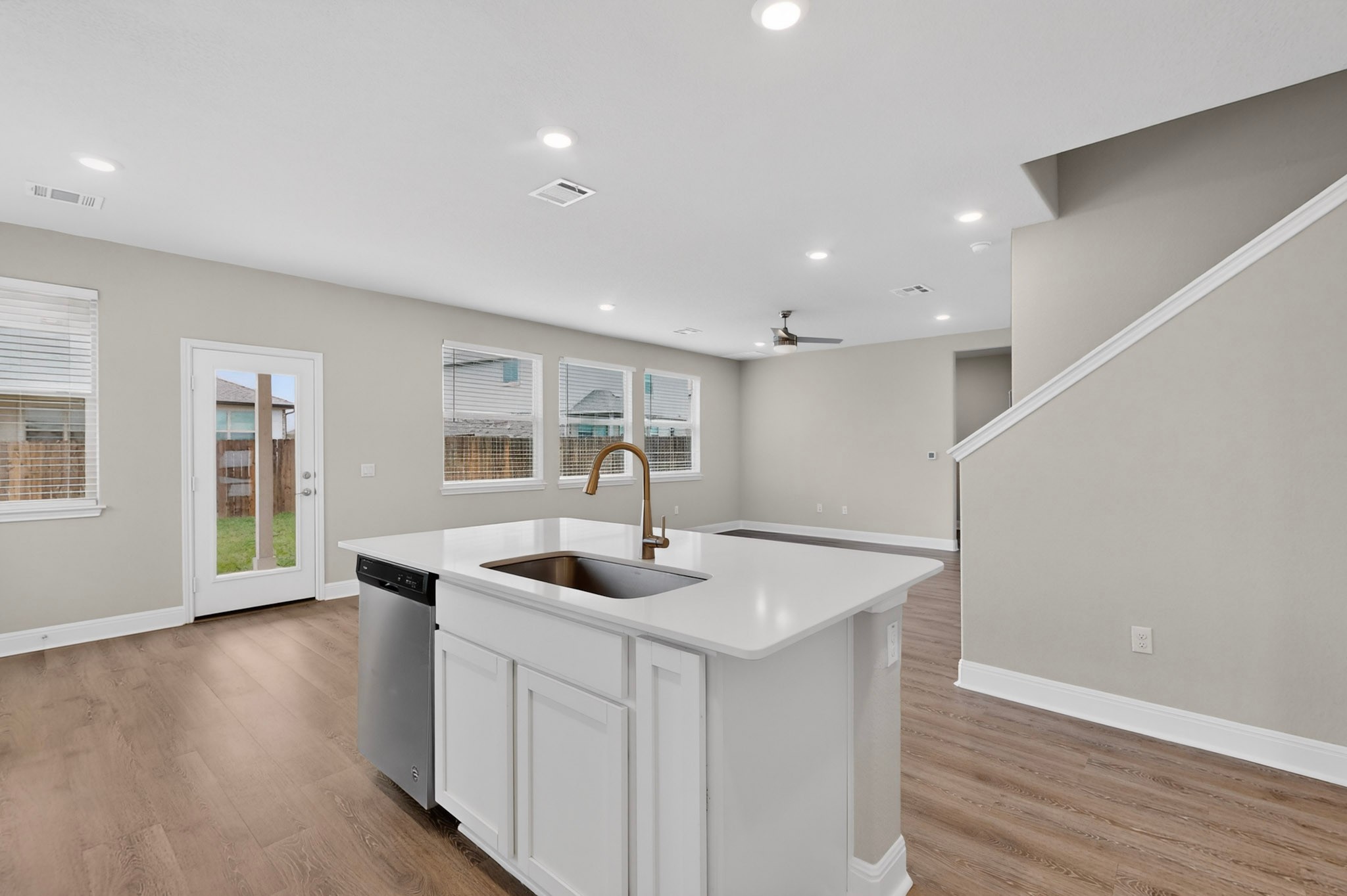 16809 Guido Cove Pflugerville, TX 78660 - Photo 13 of 40 Kitchen island with a white countertop and integrated sink, stainless steel dishwasher, and a bronze-finish faucet