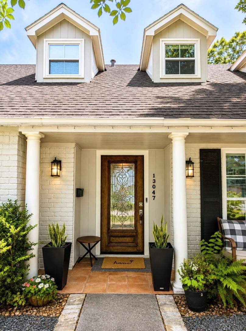 13047 Taylorcrest Road Houston, TX 77079 - Photo 2 of 23 A closer look at the welcoming covered front porch showcases the decorative glass front door, classic columns, & thoughtfully landscaped entry, creating a warm first impression as you arrive home.