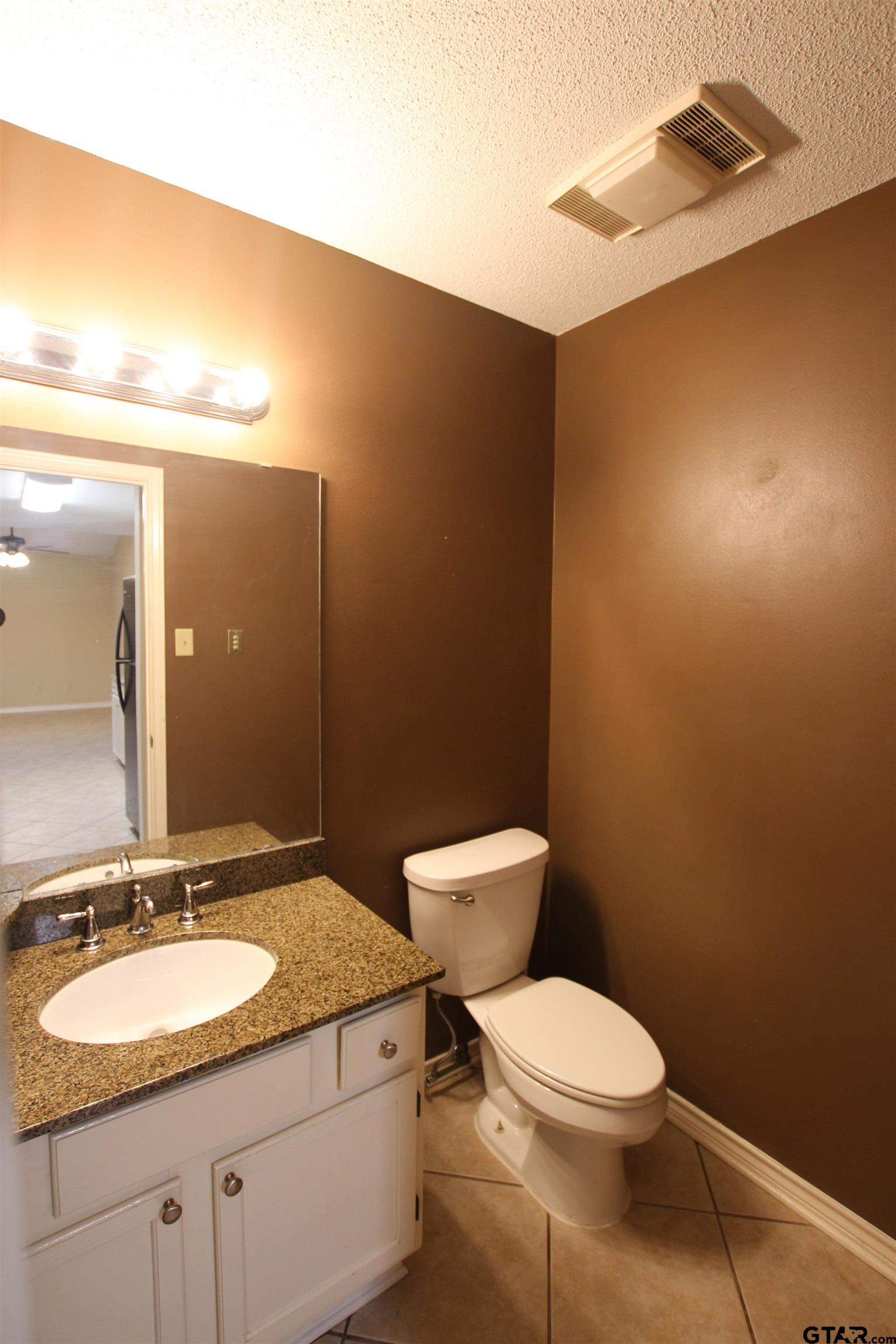 5875 Creekside Circle Tyler, TX 75703 - Photo 14 of 32 a bathroom with a granite countertop sink mirror vanity and toilet