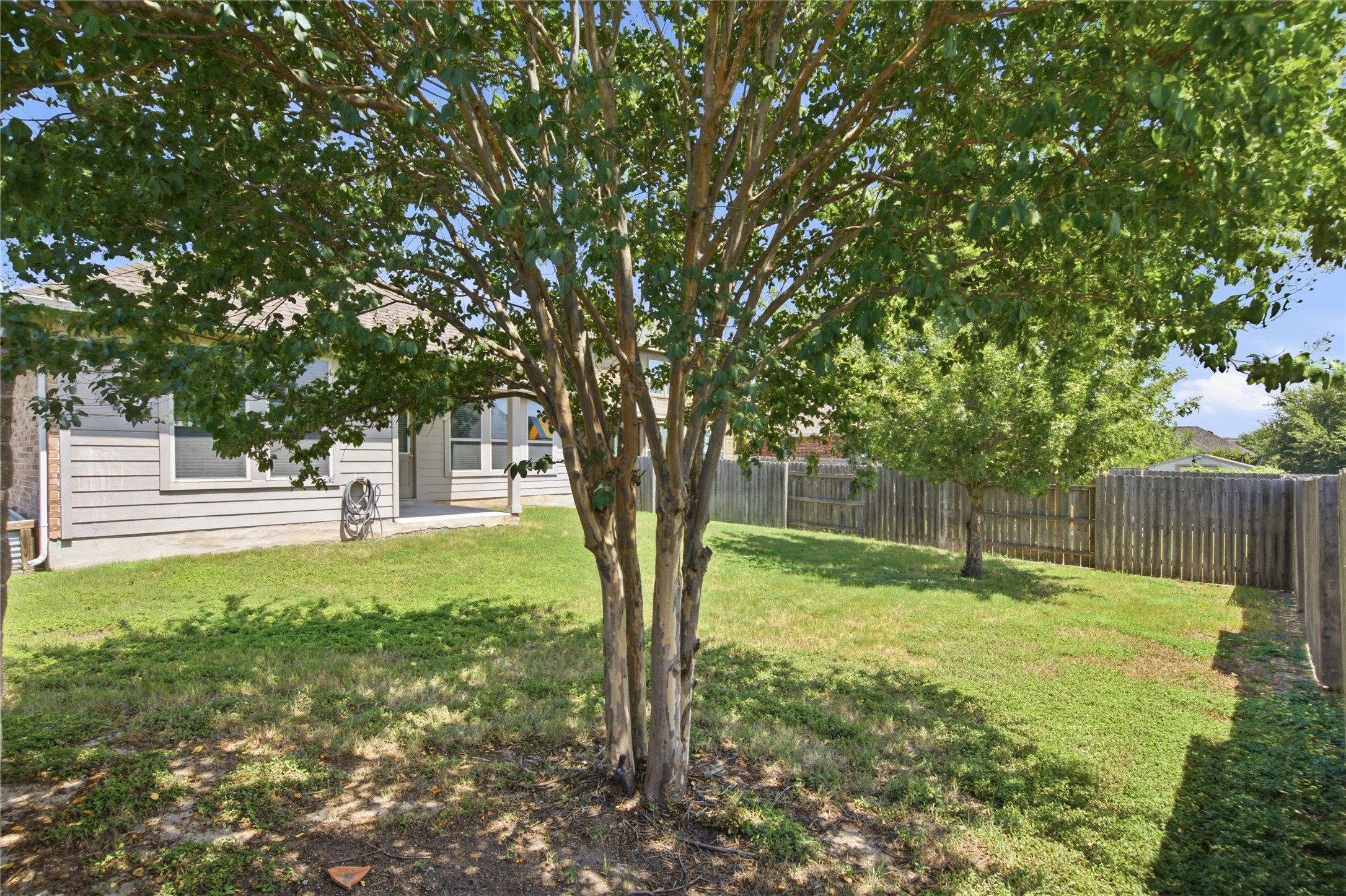 2601 Rough Berry Road Pflugerville, TX 78660 - Photo 34 of 36 A verdant backyard with mature trees and a sturdy wood fence offers a private outdoor haven.