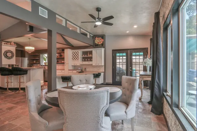 a kitchen with granite countertop a sink a stove a dining table and chairs