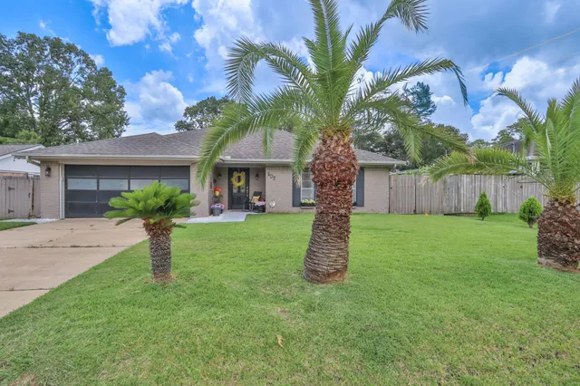 a view of a house with a yard and palm trees