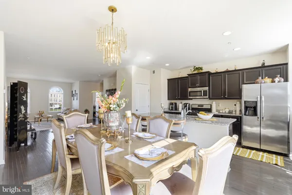 a view of a dining room with furniture a kitchen and chandelier