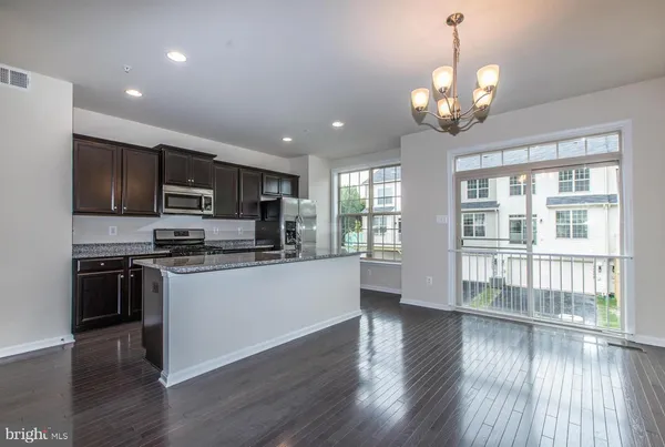a large kitchen with stainless steel appliances granite countertop a stove top oven a refrigerator with wooden floors and cabinets