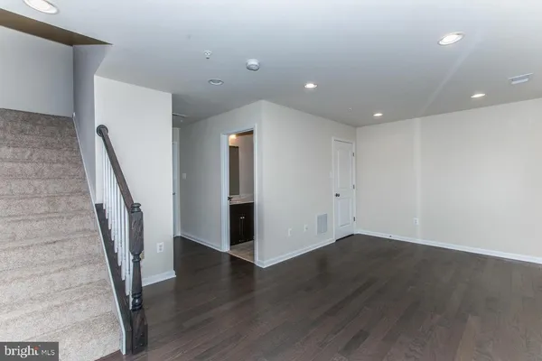 a view of an empty room with wooden floor and stairs