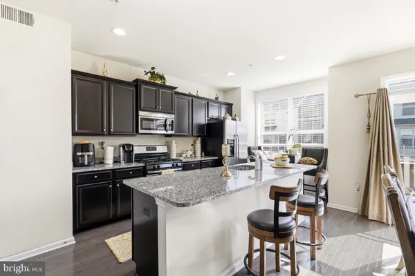 a kitchen with stainless steel appliances granite countertop a stove top oven a sink dishwasher a dining table and chairs with wooden floor