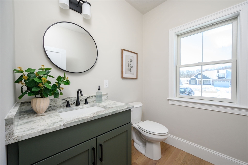 78 Metacomet Road, Unit 78 West Bridgewater, MA 02379 - Photo 22 of 39 a bathroom with a granite countertop toilet a sink a mirror and a window