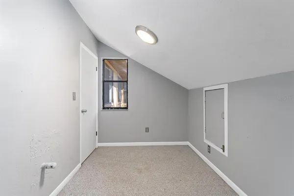 a view of an empty room with window and closet area