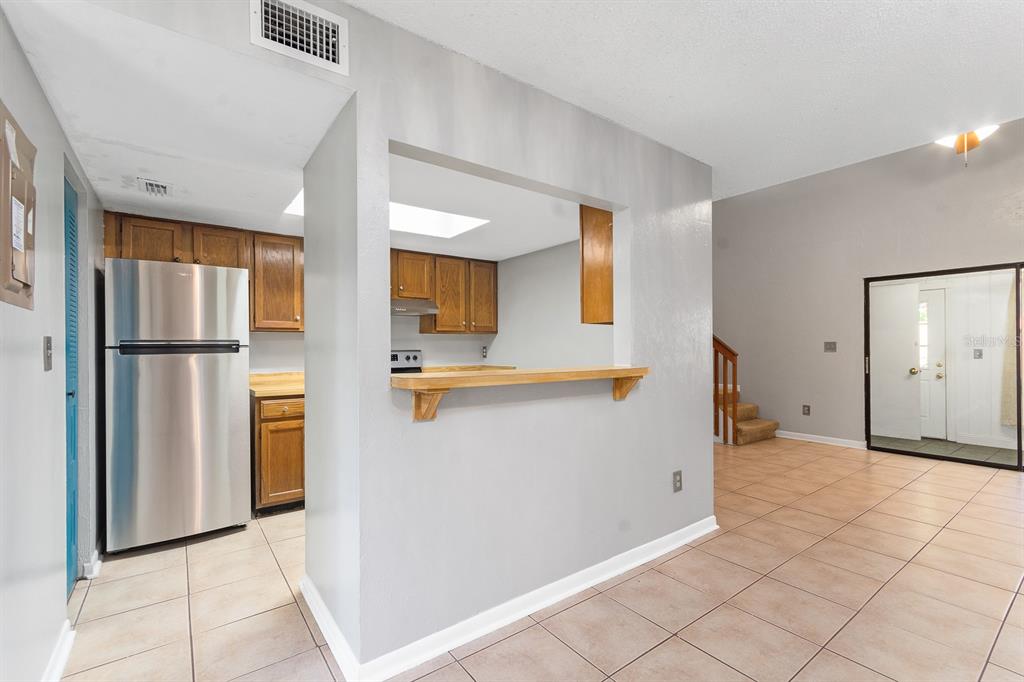 6926 Southwest 45th Avenue Gainesville, FL 32608 - Photo 8 of 28 a view of a refrigerator in kitchen and an empty room in wooden floor