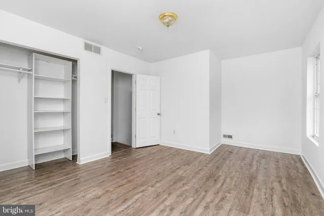 a view of an empty room with a window and wooden floor