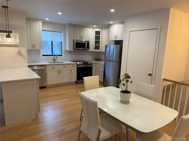 a kitchen with stainless steel appliances a dining table chairs microwave and sink
