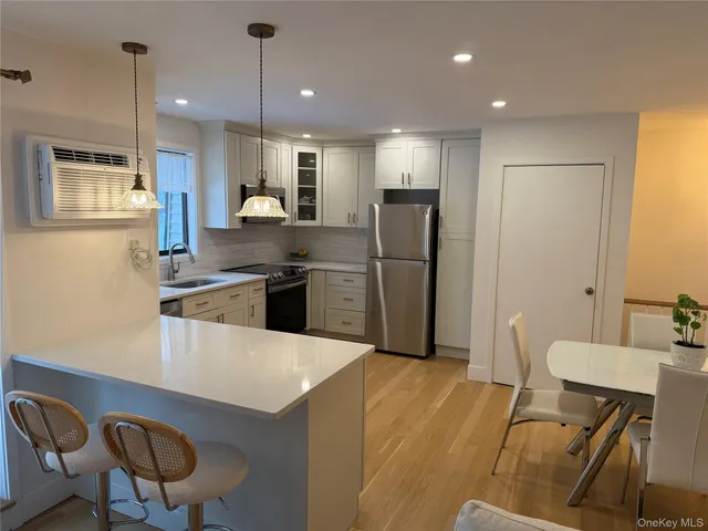 a kitchen with stainless steel appliances kitchen island granite countertop a refrigerator a stove a sink a dining table and chairs with wooden floor