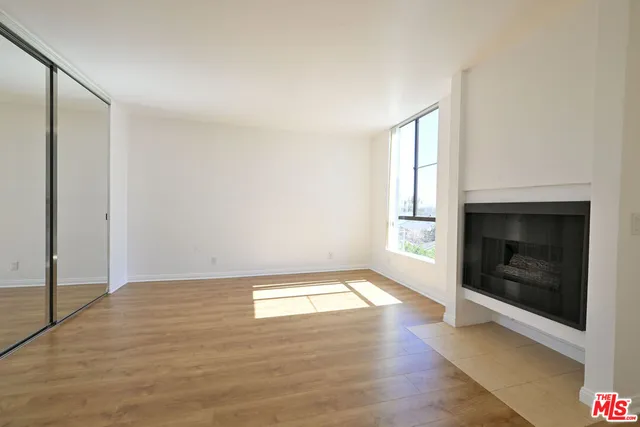 a view of an empty room with window and fire place