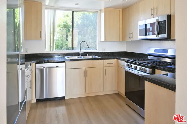 a kitchen with stainless steel appliances granite countertop a stove a sink and white cabinets