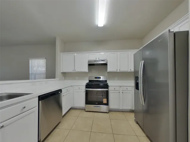 a kitchen with stainless steel appliances granite countertop a stove a refrigerator and a sink