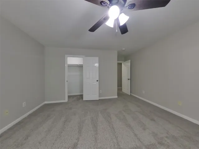 an empty room with chandelier fan and windows