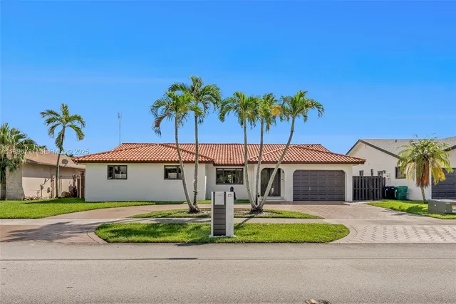 a front view of a house with a garden and palm trees