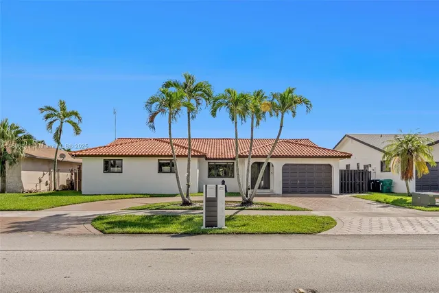 a front view of a house with a garden and palm trees