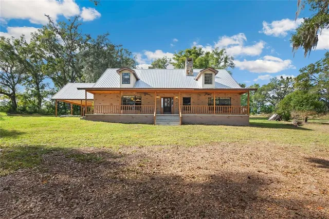 a front view of house with yard and trees in the background
