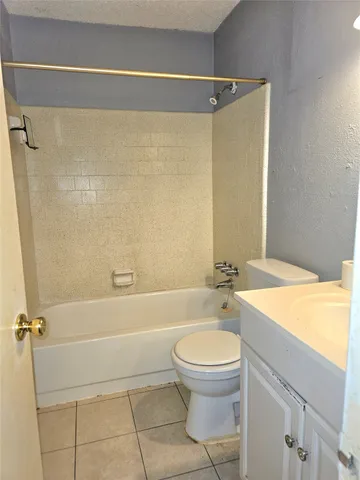 a bathroom with a granite countertop bathtub shower sink vanity and toilet
