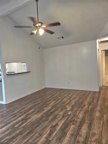 a view of an empty room with window and wooden floor
