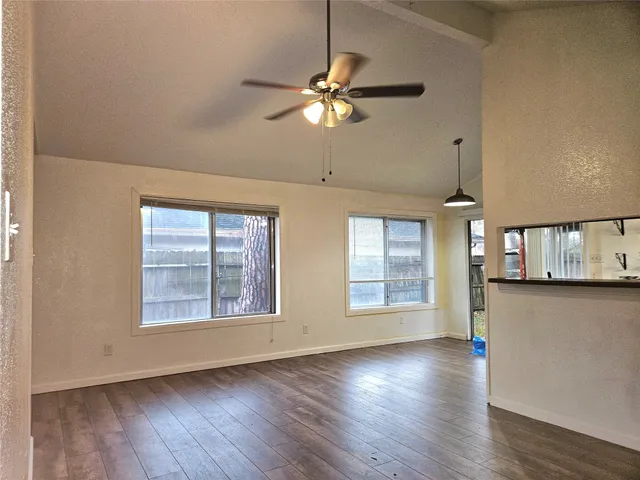 a view of an empty room with window and wooden floor