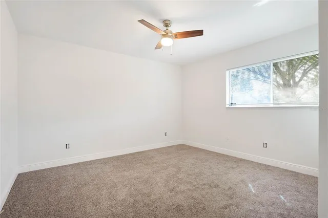 an empty room with a window and a ceiling fan