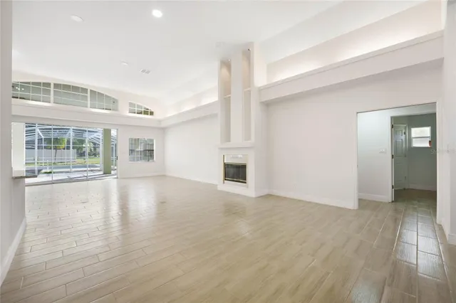 a view of an empty room with glass door and wooden floor