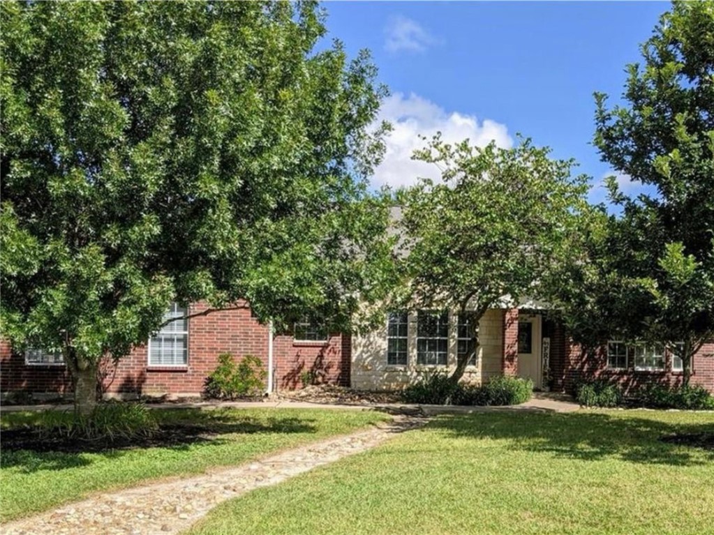a front view of a house with a garden and tree